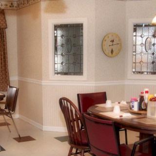 A cozy dining room with a round table set for breakfast, featuring wooden chairs and decorative windows.