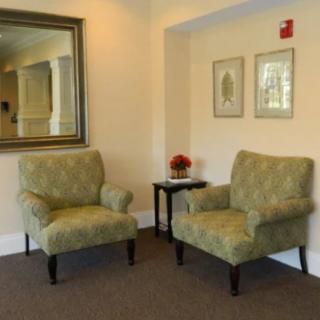 A cozy seating area with two upholstered chairs, a small side table, and decorative elements including a mirror and framed artwork.