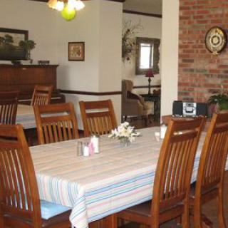 A cozy dining area with a wooden table and chairs, decorated with a striped tablecloth and centerpiece.