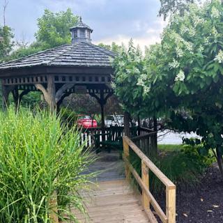 A serene gazebo surrounded by lush greenery, inviting visitors to relax and enjoy the natural beauty.