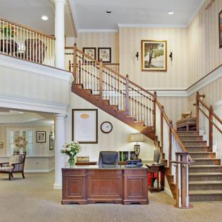 A welcoming lobby with a wooden reception desk and elegant staircase.