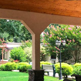 A scenic garden view from a covered patio, featuring lush greenery and a cozy bench.