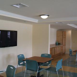 A modern cafe interior with tables, chairs, and a wall-mounted television.