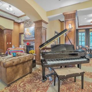 A luxurious living room featuring a grand piano, cozy sofa, and elegant decor.