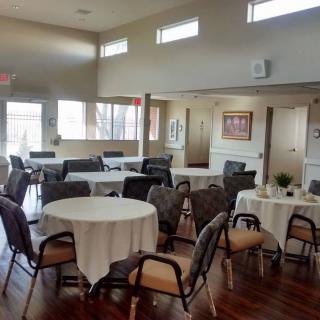 A well-lit, organized event space with round tables and chairs set up for dining.