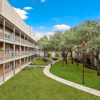 A view of an apartment building with a well-maintained courtyard and landscaped garden.