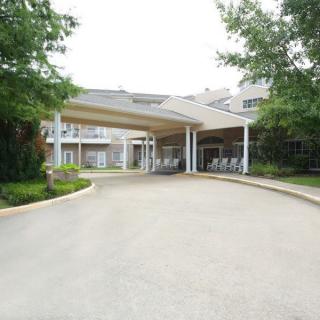 A building entrance with a covered driveway and surrounding greenery.