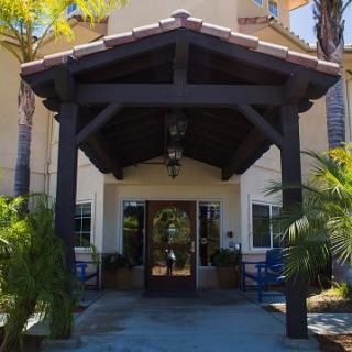 A building entrance with a wooden awning and surrounding palm trees.