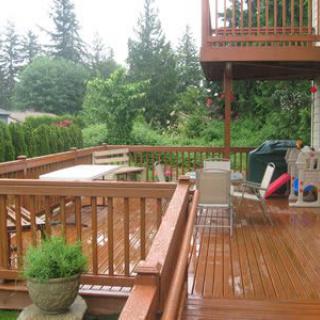 A wooden deck with outdoor furniture surrounded by lush greenery.
