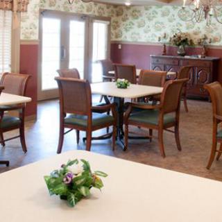 A cozy dining area with neatly arranged tables and chairs, featuring floral decorations.
