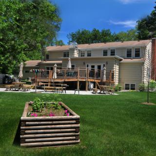 A spacious backyard featuring a large wooden deck and a garden box on a well-maintained lawn.