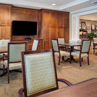 A cozy and elegantly furnished dining area with a television, featuring wooden paneling and neatly arranged tables and chairs.