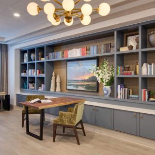 A modern home office with a large bookshelf, stylish desk, and elegant lighting.