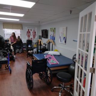 A rehabilitation room equipped with wheelchairs, therapy tables, and exercise equipment.