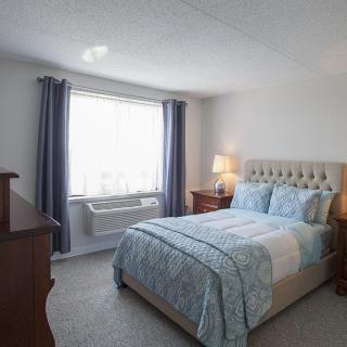 A cozy bedroom with a bed, nightstands, and a window with curtains.