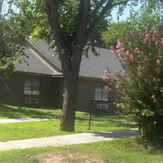 A serene view of a house surrounded by greenery and blooming flowers.