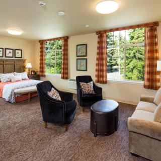 A cozy bedroom with large windows, featuring comfortable seating and stylish decor.