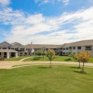 A spacious two-story residential building with a manicured lawn on a clear day.