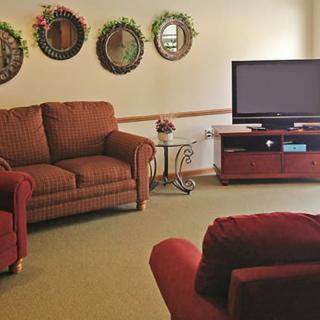 A cozy living room with comfortable seating, a TV, and decorative wall mirrors.