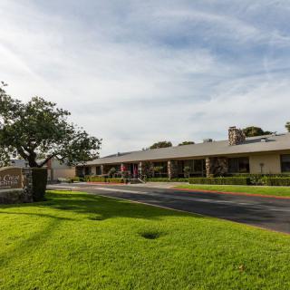 A building with a well-maintained lawn and a tree, set against a clear sky.
