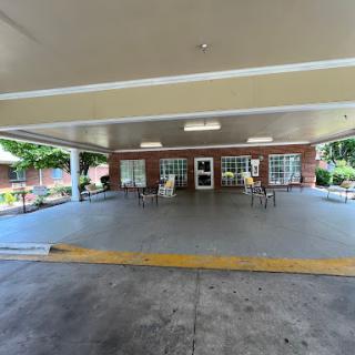 A spacious entrance area with a covered roof and chairs arranged for seating.