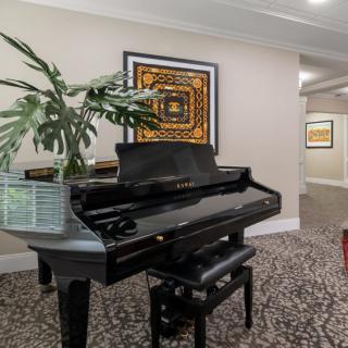A grand piano in a stylish hallway with artwork and plants.