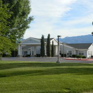 A serene view of a hospitality building surrounded by greenery and mountains in the background.