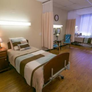 A hospital room with a single bed, bedside table, and curtain dividers.