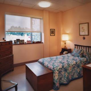A cozy bedroom featuring floral bedding, warm lighting, and classic wooden furniture.