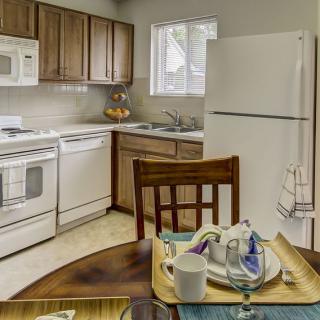 A cozy kitchen with wooden cabinets and white appliances, featuring a small dining table set for a meal.