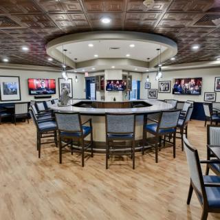 A modern bar area with circular seating, multiple TVs, and stylish lighting.