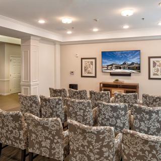 A small conference room with patterned chairs facing a TV for presentations.