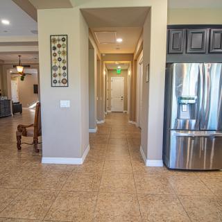 A modern kitchen with a stainless steel refrigerator and a long hallway.
