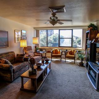 A cozy living room with comfortable seating, large windows, and warm lighting.