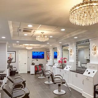 A luxurious modern salon interior with chandeliers and seating areas.