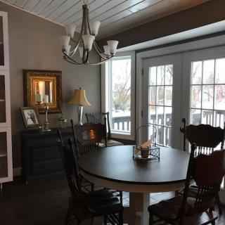 A cozy dining room with a round table, chairs, and a chandelier, illuminated by natural light from the French doors.