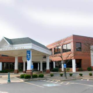 The exterior of a hospital building with an entrance canopy and accessible parking spaces.