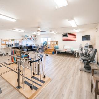 A spacious rehabilitation therapy room equipped with various exercise tools and an American flag adorning the wall.