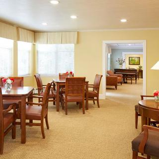A bright dining area featuring wooden tables and chairs with large windows allowing natural light.