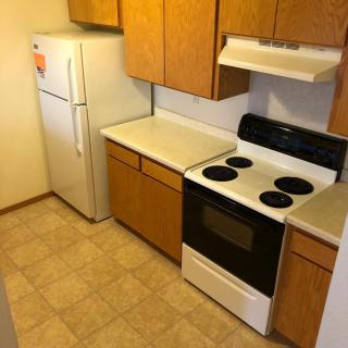 A small kitchen featuring a stove, refrigerator, and wooden cabinets.