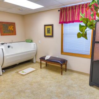 A clean and cozy room with a bathtub, bench, and decorative elements.