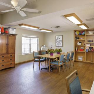A cozy, well-lit room with a table and chairs, wooden furniture, and a bookshelf.