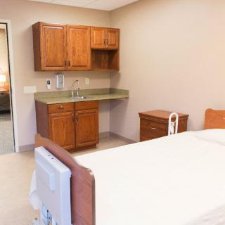 A clean and well-organized hospital room with a bed, cabinets, and a sink.