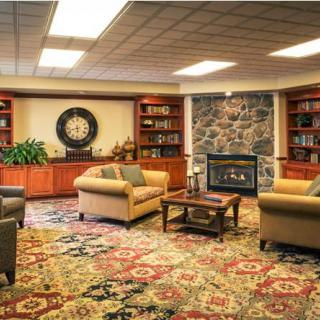 A cozy living room with comfortable sofas, a stone fireplace, and bookshelves lining the walls.