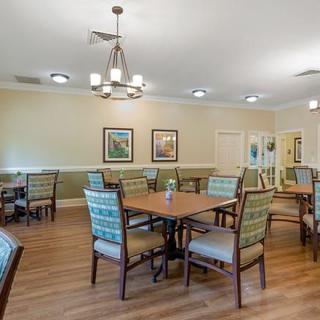 A well-lit dining area with multiple tables and chairs, featuring modern decor and artwork on the walls.