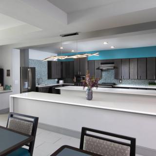 A modern kitchen space with a large countertop and dining area.