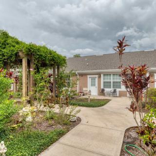 A beautifully landscaped garden with a pathway leading to a house under a cloudy sky.