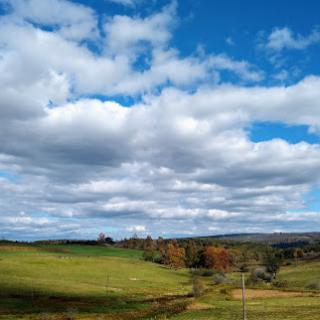 A serene landscape showcasing a vibrant green field under a partly cloudy sky.