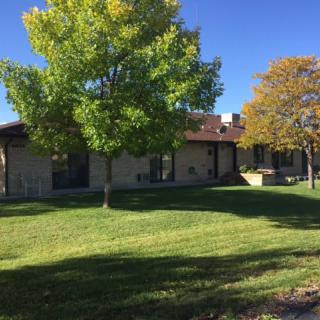 A suburban house with a well-maintained lawn and trees on a sunny day.