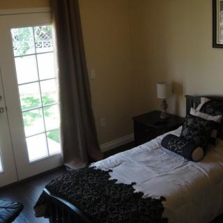 A cozy bedroom with a single bed and French doors leading outside.